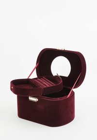 Bordowe welurowe pudełko na biżuterię o zaokrąglonym, wyraźnie zdefiniowanym kształcie. Zawiera wyjmowaną wyściełaną przegrodę i złote zapięcie na zatrzask.