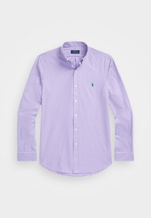 Camisa de cuadros morados con botones y mangas largas, que presenta un pequeño logo verde en el pecho izquierdo. La tela parece suave y liviana.