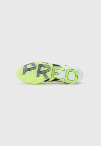 Suela de botas de fútbol negra y verde neón con superficie texturizada, que presenta grandes letras "PRED" y un diseño colorido.