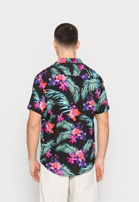 Short-sleeved black shirt featuring vibrant floral and palm leaf patterns in pink, purple, and teal, with a relaxed fit and classic collar.
