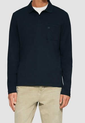Mørkeblå langærmet polo shirt lavet af bomuld, med krave, en brystlomme og subtile logodetaljer. Matchet med beige bukser.