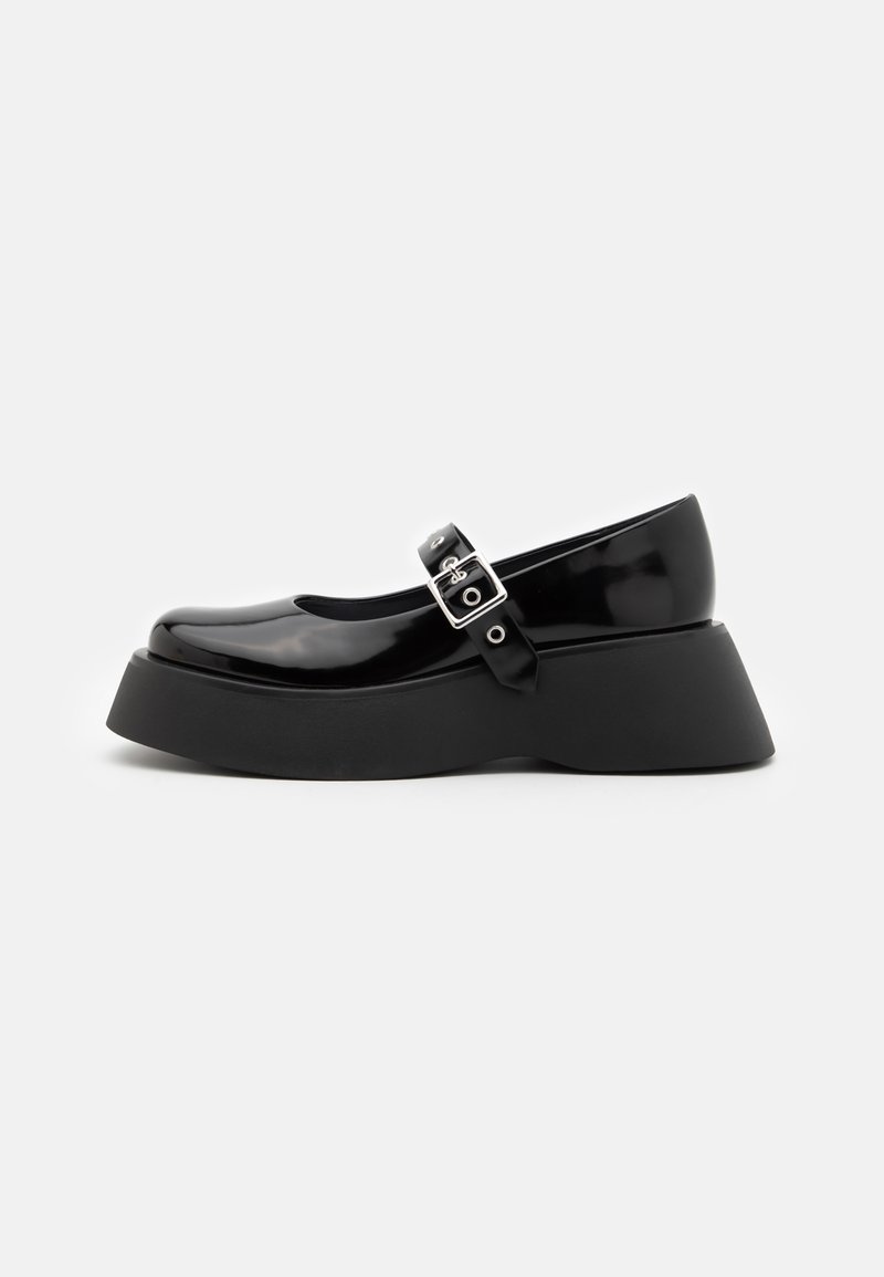 Black patent leather Mary Jane shoes with a rounded toe, adjustable ankle strap, and thick black platform sole.