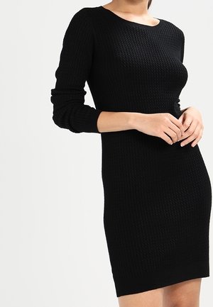 Abito nero a maglia con una texture a coste, maniche lunghe e scollo rotondo. Design aderente che termina sopra il ginocchio.