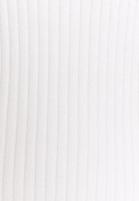 Tessuto bianco a costine con una finitura testurizzata, caratterizzato da righe verticali e un aspetto morbido. Il materiale è probabilmente composto da cotone o un misto di cotone.