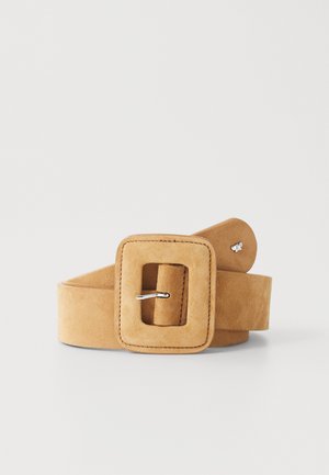 Suedesnorregurt i lys tan, med en stor kvadratisk spænde med sølvfarvet hardware. Blød tekstur med en glat finish og diskret syningsdetalje.