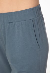 Lichtblauwe, zachte stoffen broek met een elastische tailleband. Heeft een zijzak en een losse pasvorm, geschikt voor casual draag.