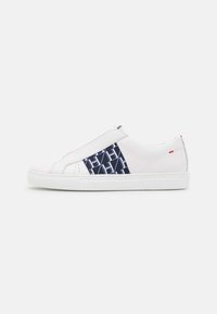 Sneaker bianca senza lacci con motivo navy testurizzato di lato, suola in gomma e design minimalista con un sottile accento rosso vicino al tallone.