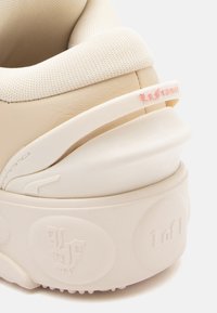 Beež nahast spordijalatsid tekstureeritud ülemise osaga, kummist välistallaga ning diskreetse roosa "LaFranda" brändingu jaotusega kand. Ümar kuju kihilise disainiga.