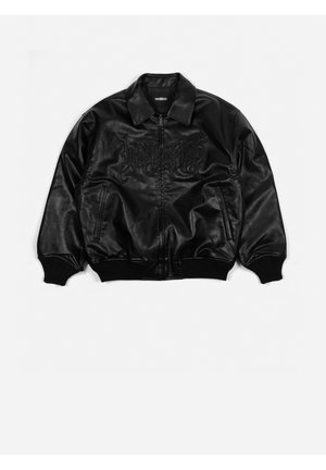 Musta tekonahkainen bomber-takki, jossa edessä vetoketju, resorimitatut hihansuut ja helma, kaksi sivutaskua ja rintakehässä kohopainettu goottilaistyylinen teksti.