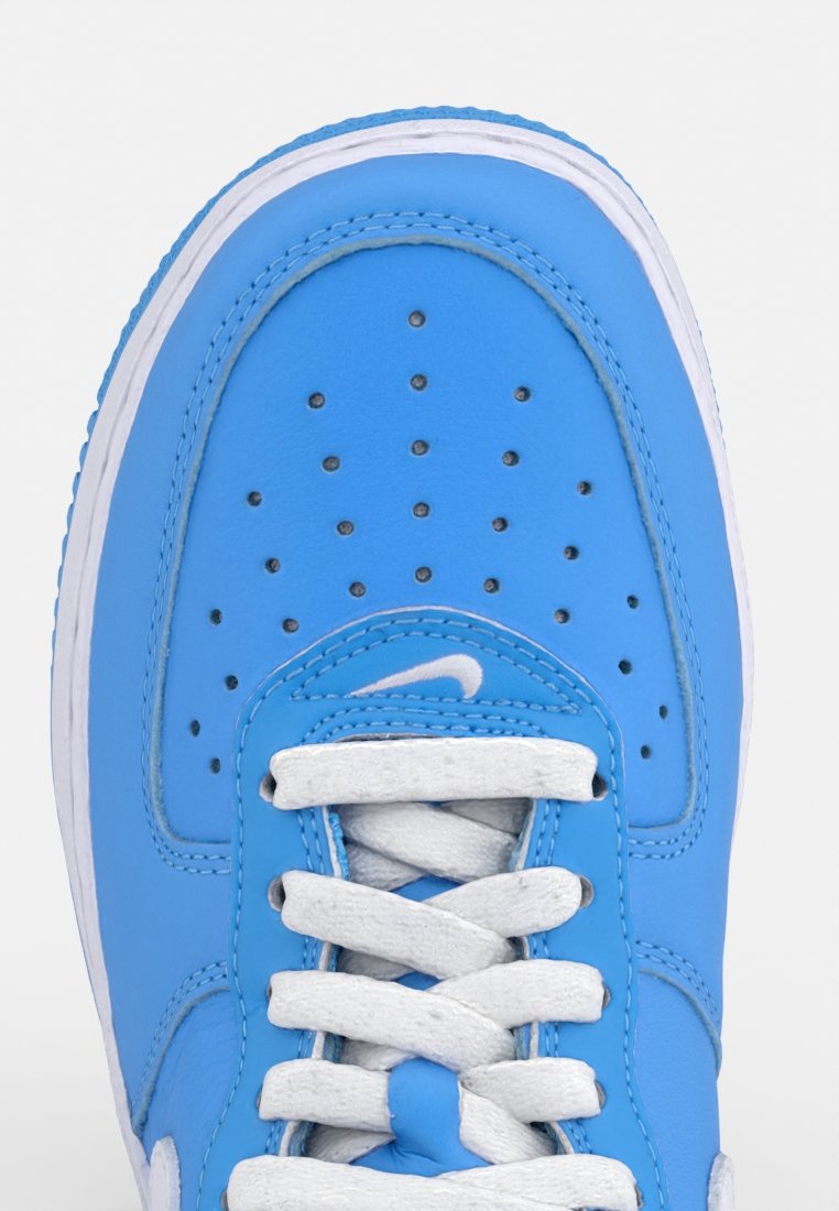 Sneaker blu in pelle con lacci bianchi, dotato di punta perforata e intersuola bianca a contrasto. Forma arrotondata con texture liscia.