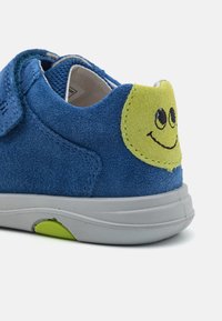 Blaue Wildlederschuhe mit grauer Sohle; mit einem grünen Smiley-Gesicht Detail an der Ferse und einem Klettverschluss für einen sicheren Sitz.