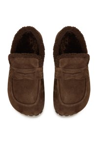 Een paar bruine suède instapslippers met een dikke fleece voering en decoratieve banddetail, gezien van bovenaf tegen een witte achtergrond.