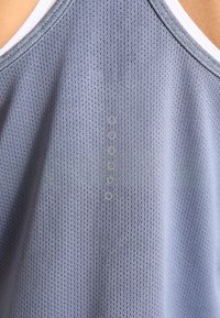 Světlomodrý sportovní top z prodyšné síťoviny, s kulatým výstřihem a pěti ozdobnými knoflíky na zádech.