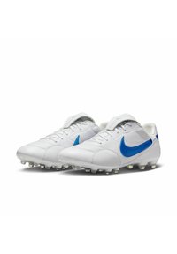Botas de fútbol blancas con el swoosh azul de Nike, fabricadas en material sintético suave y texturizado, presentan un perfil bajo y tacos moldeados.