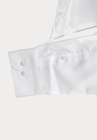 Camisa de cuello blanco con puños abotonados, que presenta un tejido suave y costuras precisas. Dos botones visibles en cada puño.