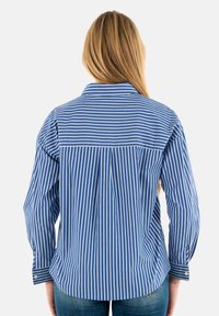 Camisa de botones a rayas azul y blanca con cuello, mangas largas y dobladillo curvado. Presenta un diseño de yugo con rayas verticales.