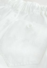 Pantalons en coton blanc avec une taille élastique, comportant une poche arrière fermée par un bouton blanc et une finition légèrement texturée.