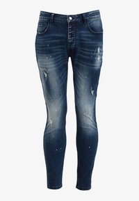 Smala jeans i mörkblå denim med blekta avsnitt och slitna detaljer. Har silverfärgade färgsplatteraccenter och klassisk femficksdesign.