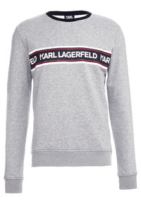 Sudadera gris de manga larga, con puños acanalados y cuello redondo. Presenta una franja horizontal con la marca "KARL LAGERFELD" en negro y rojo.
