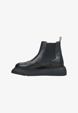 Black leather Chelsea boots with elastic sides, brogue detailing, and a chunky rubber sole. Smooth texture with a pull tab for easy wear.
