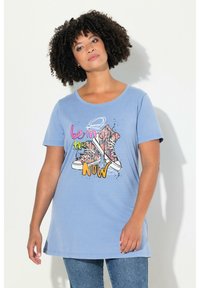 Camiseta de color azul claro con un corte holgado, que presenta un gráfico colorido de zapatillas y el texto "está en el AHORA" en tonos vibrantes. Material de algodón.