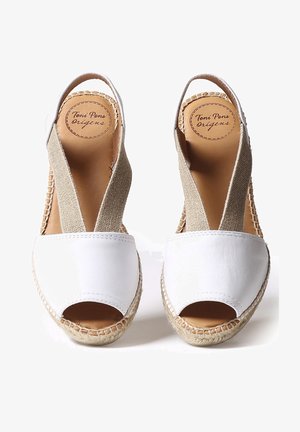 Chaussures espadrilles en cuir blanc avec bouts ouverts, brides élastiques beiges et semelles en jute tressé. Logo visible sur la doublure intérieure.