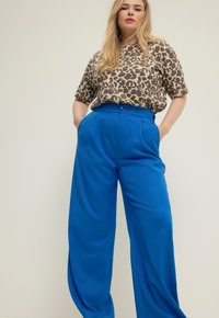 Leopardprint korte mouwen top, losse fit, gecombineerd met hoge taille, wijde blauwe broek, gladde textuur, met voorzakken en knoopdetails.