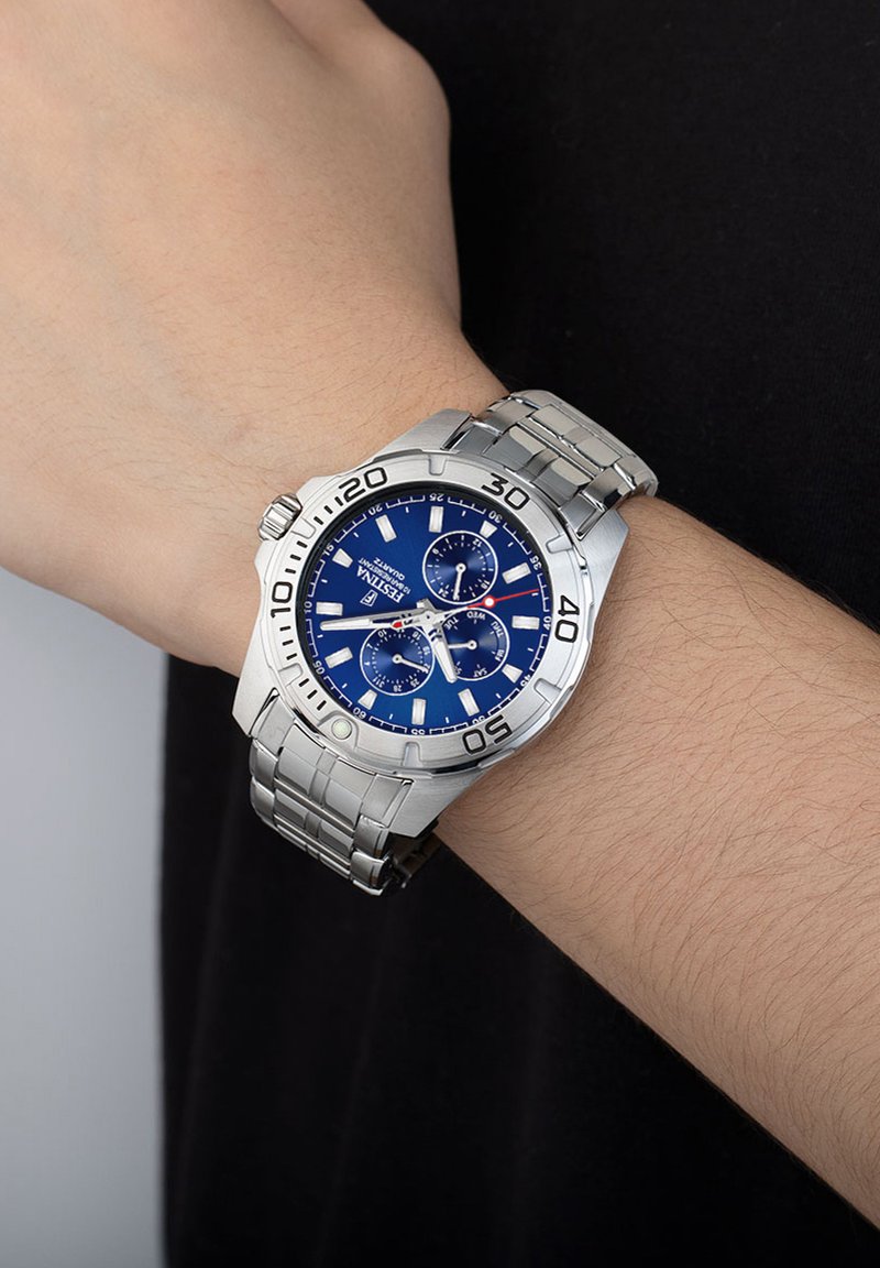 Orologio in acciaio inossidabile argentato con quadrante blu, funzionalità cronografo e lunetta marcata. Il bracciale ha una finitura spazzolata e un design a maglie.