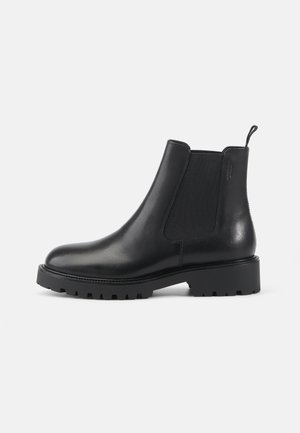 Stivale Chelsea in pelle nera con pannelli laterali elasticizzati, punta tonda, suola spessa e una linguetta sul tallone per indossarlo facilmente.