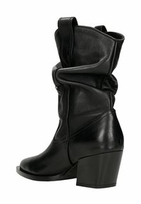 Botte en cuir noire mi-mollet avec tige décontractée, bout carré, languette et talon bloc imposant.