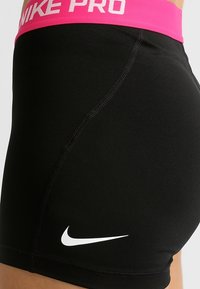 Black athletic shorts made of stretchy material, featuring a pink waistband with "NIKE PRO" text and a white Nike logo on the side.