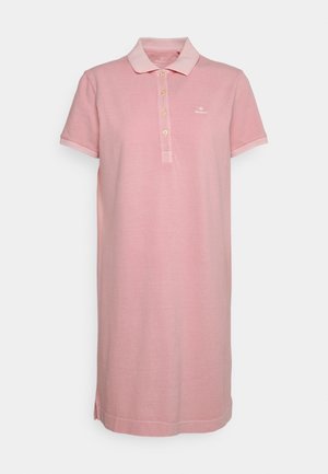 Robe polo rose clair à manches courtes avec col, quatre boutons, petit logo poitrine et fentes latérales sur fond uni.