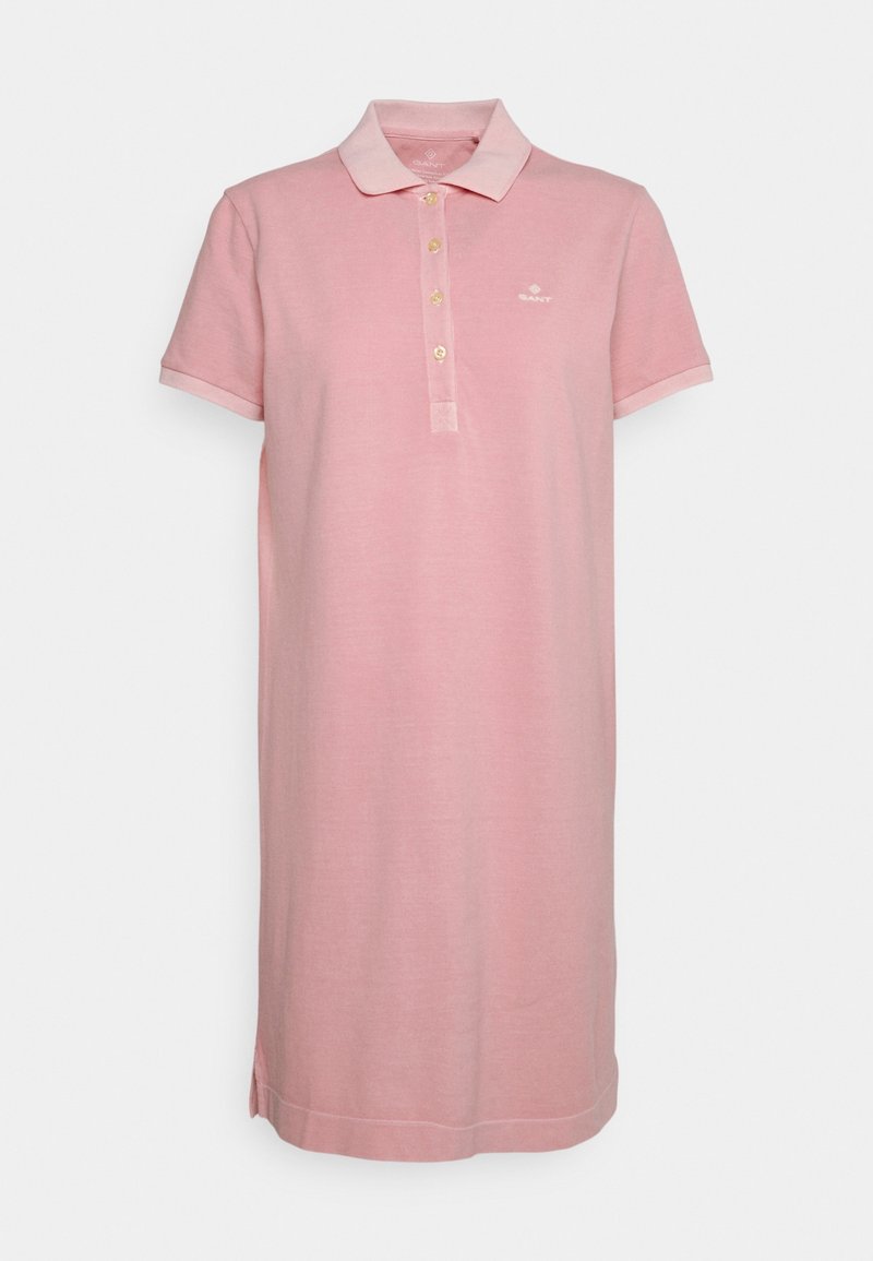 Robe polo rose clair à manches courtes avec col, quatre boutons, petit logo poitrine et fentes latérales sur fond uni.