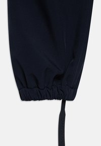 Navy elasticized pant cuff with a drawstring featuring "Viking" logo. Smooth fabric with a slightly shiny texture, minimalistic design.