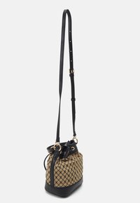 Beige og sort spandtaske med justerbar sort læderrem og guld ring accenter, med et geometrisk mønster på stofkroppen.