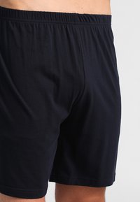 Zwarte katoenen shorts met een elastische tailleband. Eenvoudig ontwerp, gladde textuur en lengte tot midden van de dij. Geen zichtbare patronen of accenten.