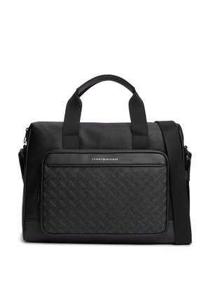 Schwarze Tommy Hilfiger Duffel-Tasche mit gewebter Fronttasche, doppelten Griffen und verstellbarem Schultergurt auf weißem Hintergrund.