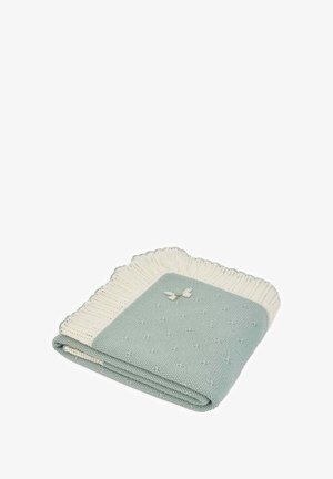 Couverture tricotée avec un fond vert menthe et une bordure côtelée couleur crème, ornée d'un petit nœud. Texture structurée avec de petits points.
