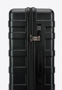 Maleta rígida negra con textura de fibra de carbono, cierre de cremallera, candado de combinación y acentos en panel elevado para mayor durabilidad y estilo.