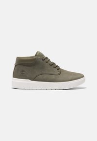 Shoe mid-top de pele verde oliva com sola de borracha branca, bico redondo e colar texturizado. Apresenta seis ilhós para atacadores e detalhe de logotipo em relevo.
