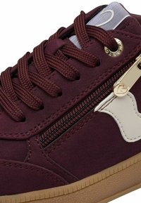 Baskets bordeaux avec une tige en textile doux, des lacets ronds, une fermeture éclair latérale en métal doré et une semelle extérieure en caoutchouc beige. Détails en cuir blanc.