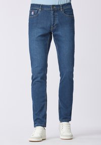 Jeans in denim blu slim fit con un classico design a cinque tasche, caratterizzati da cuciture a contrasto e un'etichetta logo discreta sulla cintura.