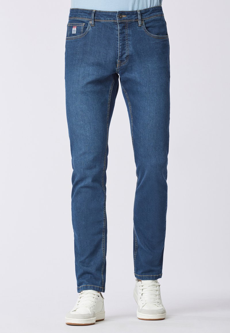 Jeans in denim blu slim fit con un classico design a cinque tasche, caratterizzati da cuciture a contrasto e un'etichetta logo discreta sulla cintura.