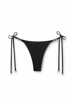 Slip bikini nero con laccetti laterali con accenti circolari dorati e anelli su sfondo bianco.