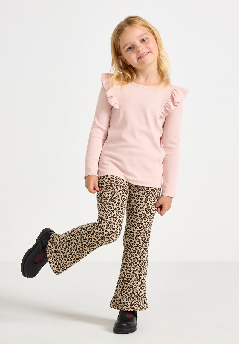 Light pink long-sleeve top with ruffled shoulders, paired with beige leopard print flared pants. Black shoes with purple accents.