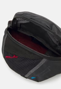 Bolsita de nylon negra con acentos de malla, interior rojo y marca azul. Cuenta con un cierre de cremallera y una superficie texturizada para un mejor agarre.