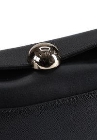 Črni usnjeni torbica z teksturirano površino, z sijočim zlatim okroglim zaponkom z vtisnjenim imenom blagovne znamke.