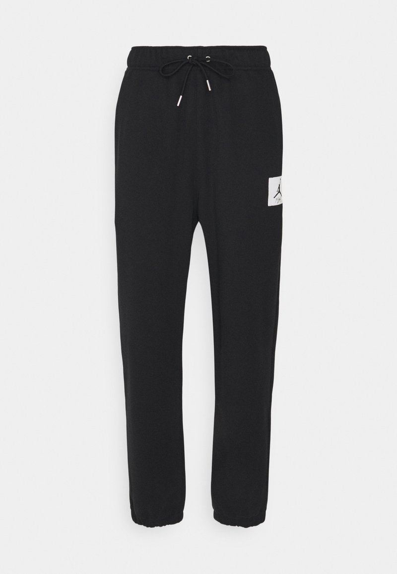 Pantalones de chándal negros de tejido suave, con cinturilla elástica y cordón, piernas ajustadas y un pequeño parche de logo en el lado izquierdo.