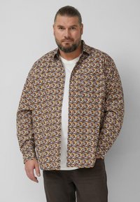 Brązowa koszula w wzory z kołnierzykiem, ozdobiona małymi żółtymi, białymi i pomarańczowymi motywami. Długie rękawy i zapinana na guziki z przodu. Nosi się ją na białym t-shircie.