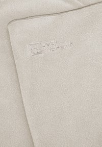 Couverture en polaire beige au toucher doux, avec le logo embossé "Jack Wolfskin" dans le coin. Design simple et lisse.